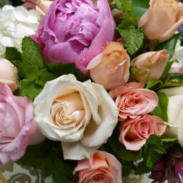 Mixed bouquet of pink, peach, and white roses with a large pink peony