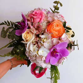 Handheld bouquet of pink, orange, and purple flowers with a ribbon