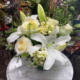 Low arrangement of white lilies and cream roses on a marble table