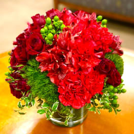 Red bouquet with roses and carnations in a glass vase