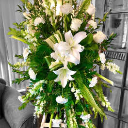 Tall white floral spray with lilies and roses on an easel