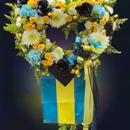 Heart-shaped floral arrangement in a blue and yellow box with ribbons