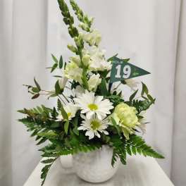 White floral arrangement in a white vase with a small green flag