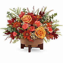 Autumn floral arrangement with orange roses and red blooms in a low container
