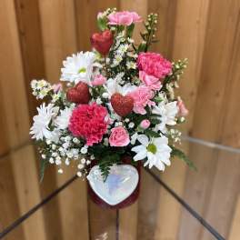 Pink and white flower arrangement with glittery red hearts in a vase
