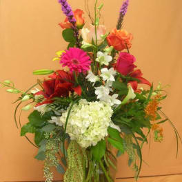 Tall mixed bouquet in a glass vase with pink, red, white, and purple flowers