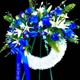 Blue and white funeral wreath on a stand with a ribbon