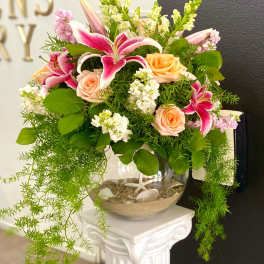 Pink lilies and peach roses arranged in a glass bowl vase