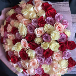 Large bouquet of red, pink, and cream roses wrapped in pale paper