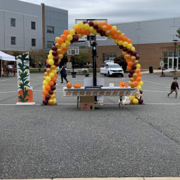 Balloon arch in yellow, orange, and burgundy at an outdoor event