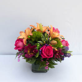 Bouquet of pink roses and orange lilies in a square glass vase