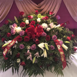 Large floral spray of red, pink, purple, and white flowers with ribbons