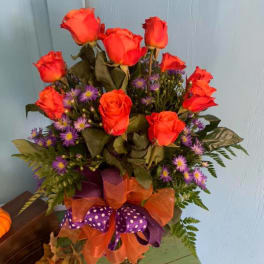 Orange roses and purple daisies in a ribboned bouquet