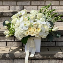 White floral arrangement in a square box with a ribbon