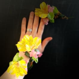Yellow and pink floral wrist corsage on a hand