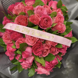 Bouquet of pink roses with a pink ribbon reading "Be My Valentine?"