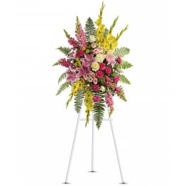 Tall standing spray of pink, yellow, and white flowers on a white easel
