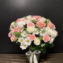 Pink and white mixed bouquet in a glass vase with a white ribbon