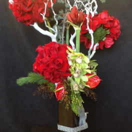 Tall floral arrangement with red roses and orchids in a square vase