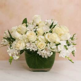 White roses and alstroemeria arranged in a green glass vase