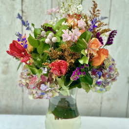 Mixed bouquet of colorful roses, tulips, and hydrangeas in a clear glass vase
