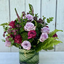 Pink and lavender roses arranged in a glass vase