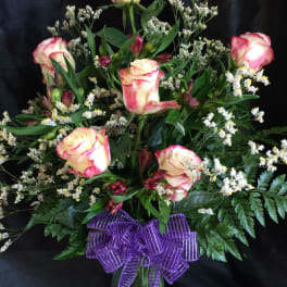 Bouquet of pink-edged white roses with a purple ribbon in a glass vase
