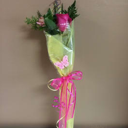 Single pink rose wrapped in green paper with a ribbon