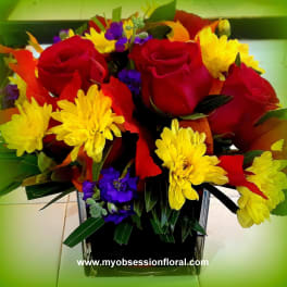 Bouquet of red roses and yellow daisies in a square glass vase