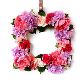 Floral wreath with pink, purple, and red blooms on a white background