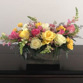 Mixed bouquet of yellow, pink, and white roses in a low container
