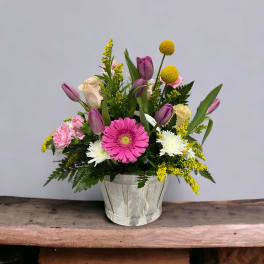 Mixed bouquet in a white wooden pot with pink, purple, yellow, and white flowers
