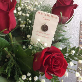 Red roses with baby's breath and a memorial charm card