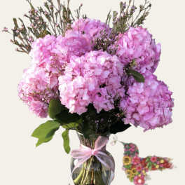 Pink hydrangea bouquet in a glass vase with a ribbon