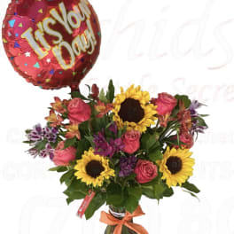 Bouquet of sunflowers, pink roses, and alstroemeria with a red "It's Your Day!" balloon