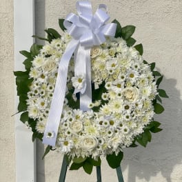 White floral wreath with a ribbon bow on an easel