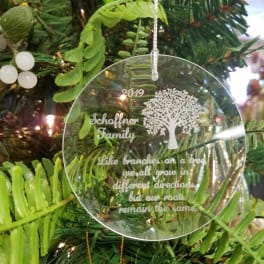 Clear ornament hanging on a Christmas tree with engraved text