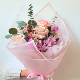 Pink and peach bouquet of roses and alstroemeria wrapped in pink paper