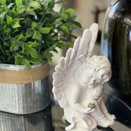 White angel figurine beside a potted green plant