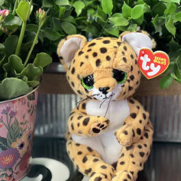 A plush leopard sits beside a potted succulent arrangement.