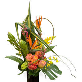 Tropical flower arrangement in a tall black vase with orange blooms and yellow accents