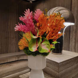 Tropical bouquet with pink and orange flowers in a white vase