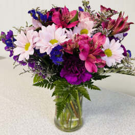Bouquet of pink daisies and magenta alstroemeria in a glass vase