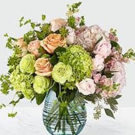 Bouquet of peach roses and green hydrangeas in a blue glass vase