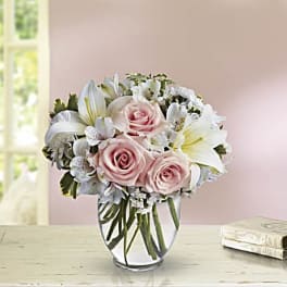 Pink roses and white lilies arranged in a clear glass vase
