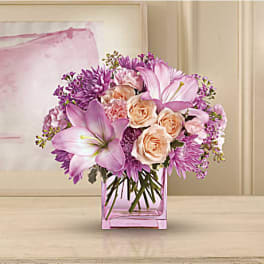 Pink and purple bouquet in a square glass vase