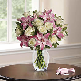 Pink lilies and white roses arranged in a clear glass vase