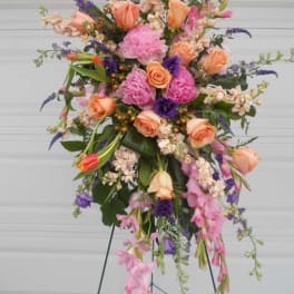 Tall standing floral spray with peach, pink, and purple flowers