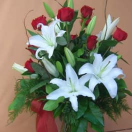 Red roses and white lilies in a glass vase with a red ribbon