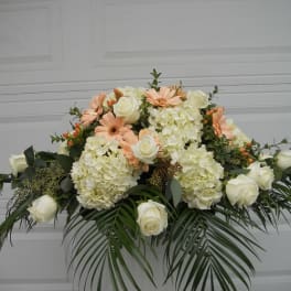 White roses and pale peach daisies in a low floral arrangement